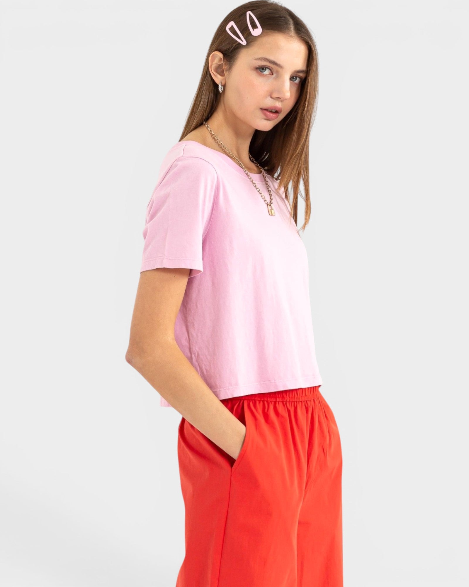 Woman wearing a pink top and red pants on a white background