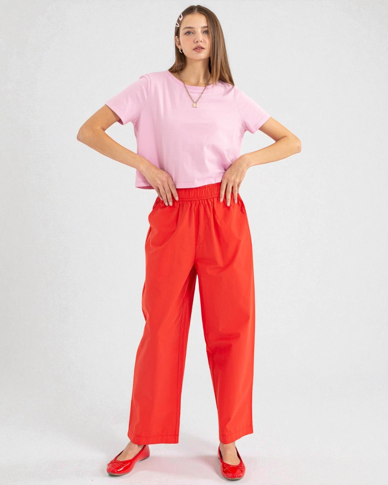 Woman wearing a pink top and red pants on a white background
