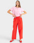 Woman wearing a pink top and red pants on a white background
