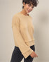 Woman wearing a beige sweater against a plain background