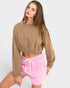Woman wearing a brown cropped sweatshirt and pink shorts on a white background