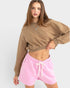 Woman wearing a brown sweatshirt and pink shorts on a white background