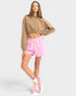 Woman wearing a brown sweatshirt and pink shorts on a white background