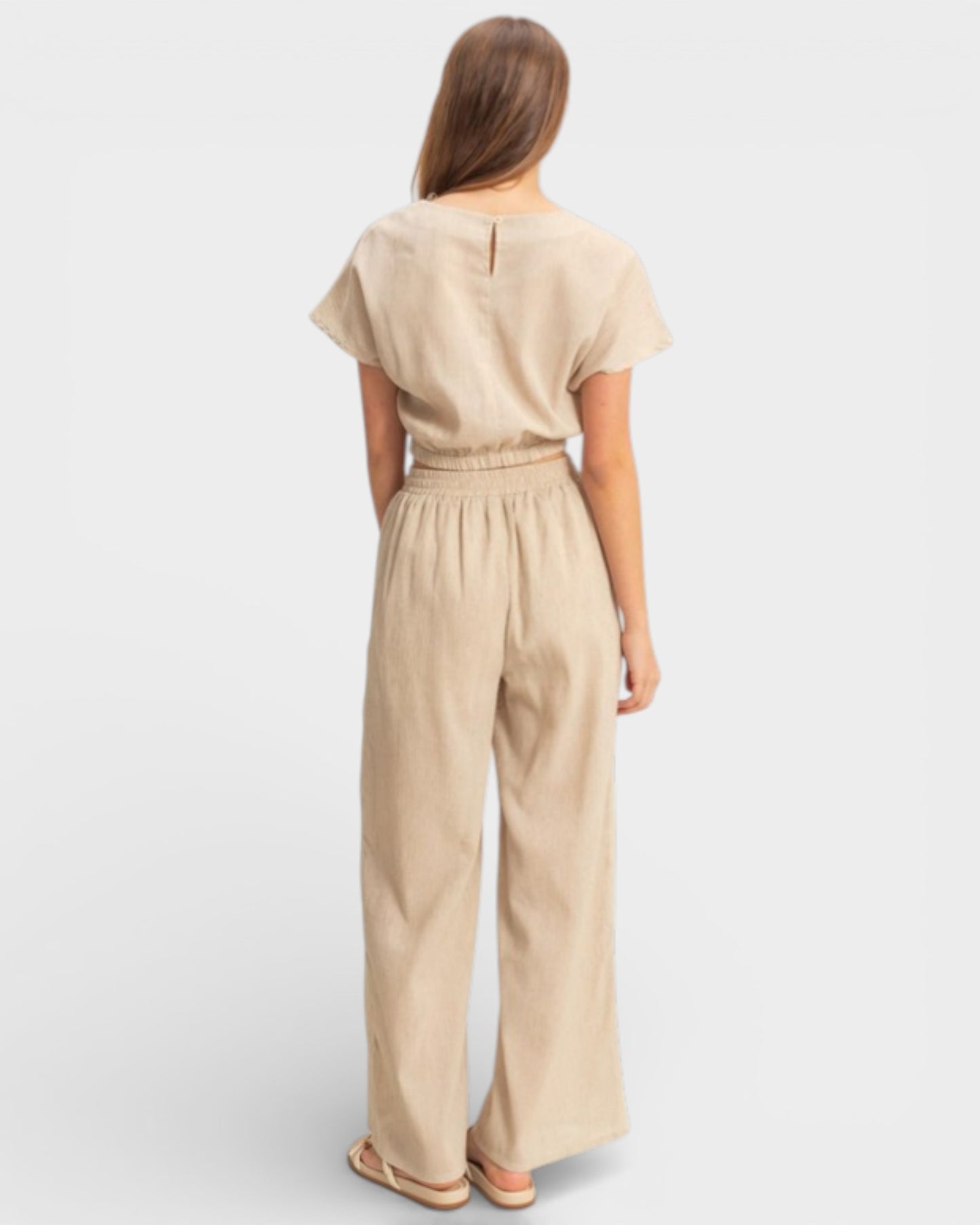 Woman wearing a beige jumpsuit on a light gray background