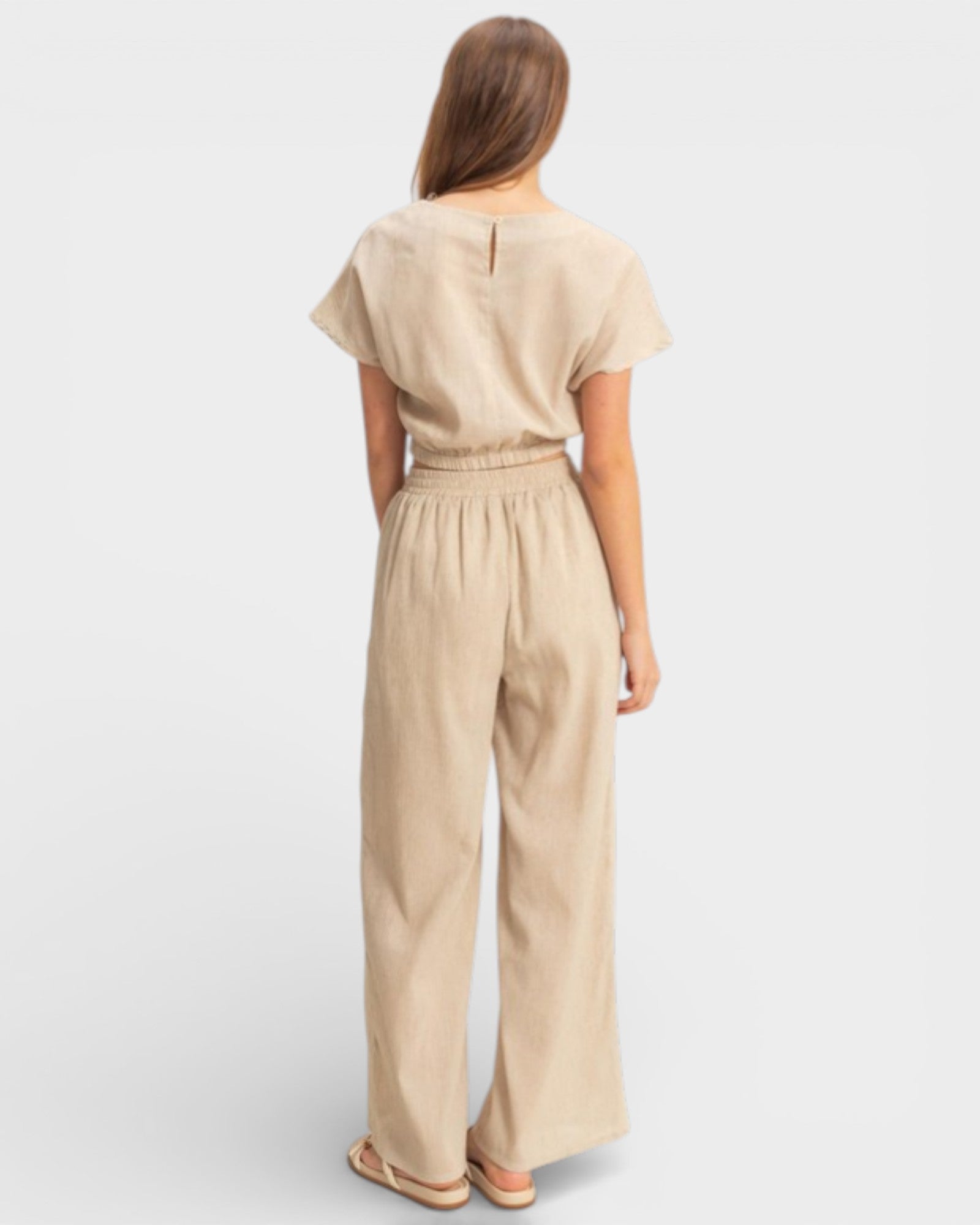 Woman wearing a beige jumpsuit on a light gray background