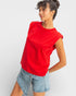 Woman wearing a red top and denim shorts on a white background