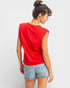Woman wearing a red sleeveless top and denim shorts on a white background