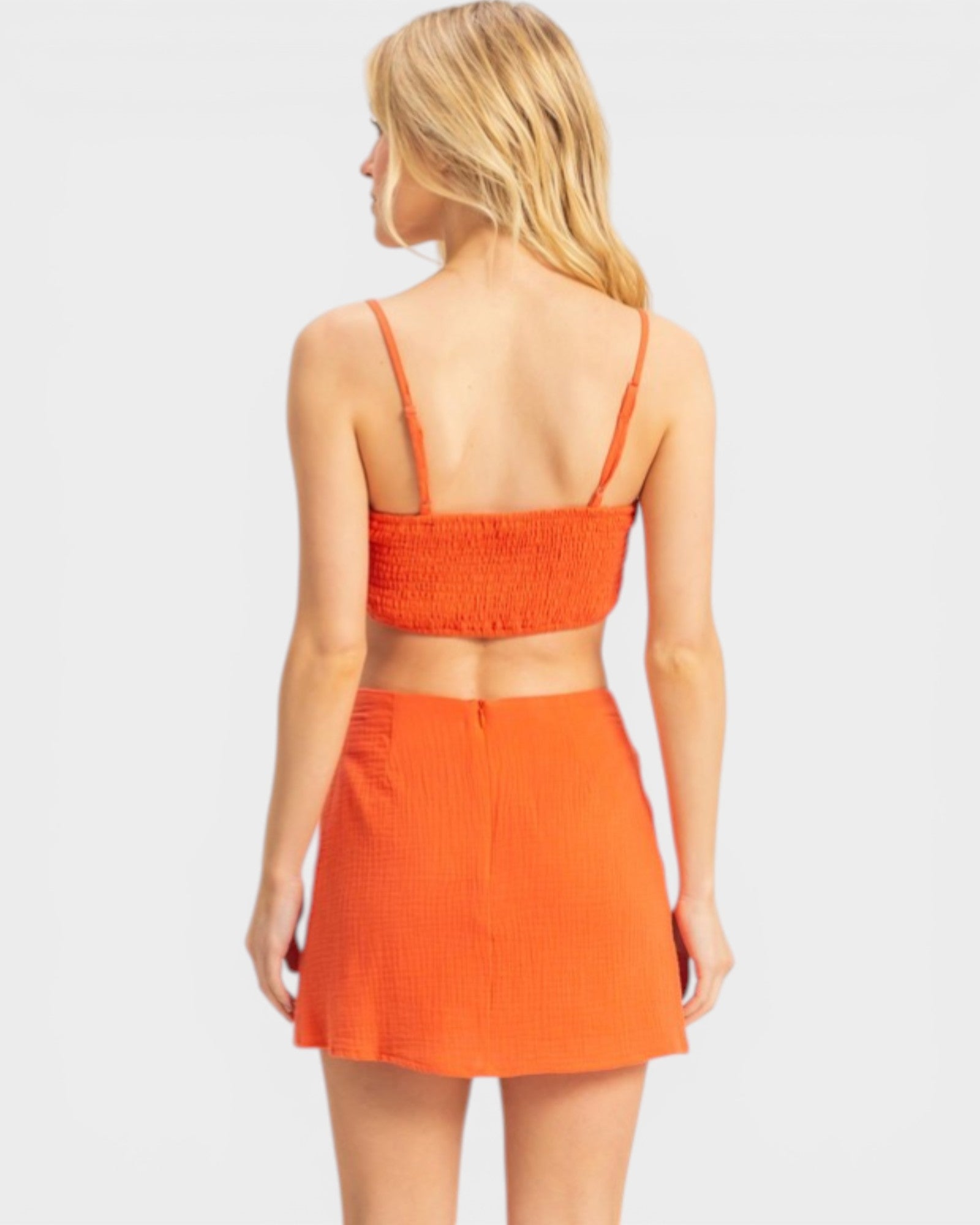 Woman wearing an orange two-piece outfit on a white background
