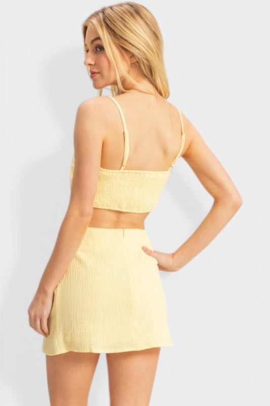 Woman wearing a yellow two-piece outfit against a white background
