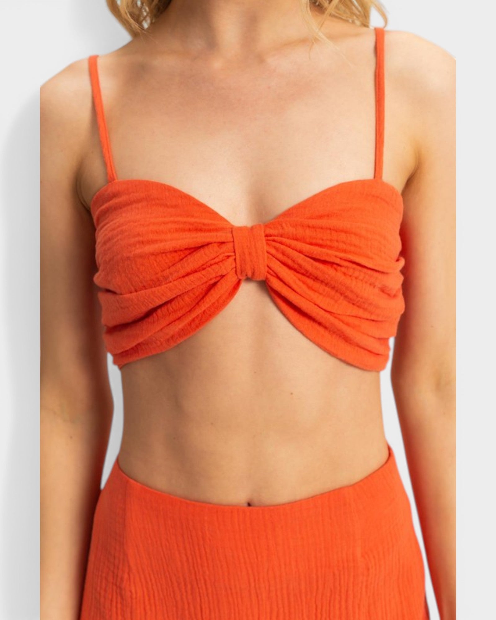 Orange bikini top worn by a person on a white background