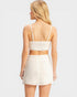 Woman wearing a white crop top and skirt set on a light gray background