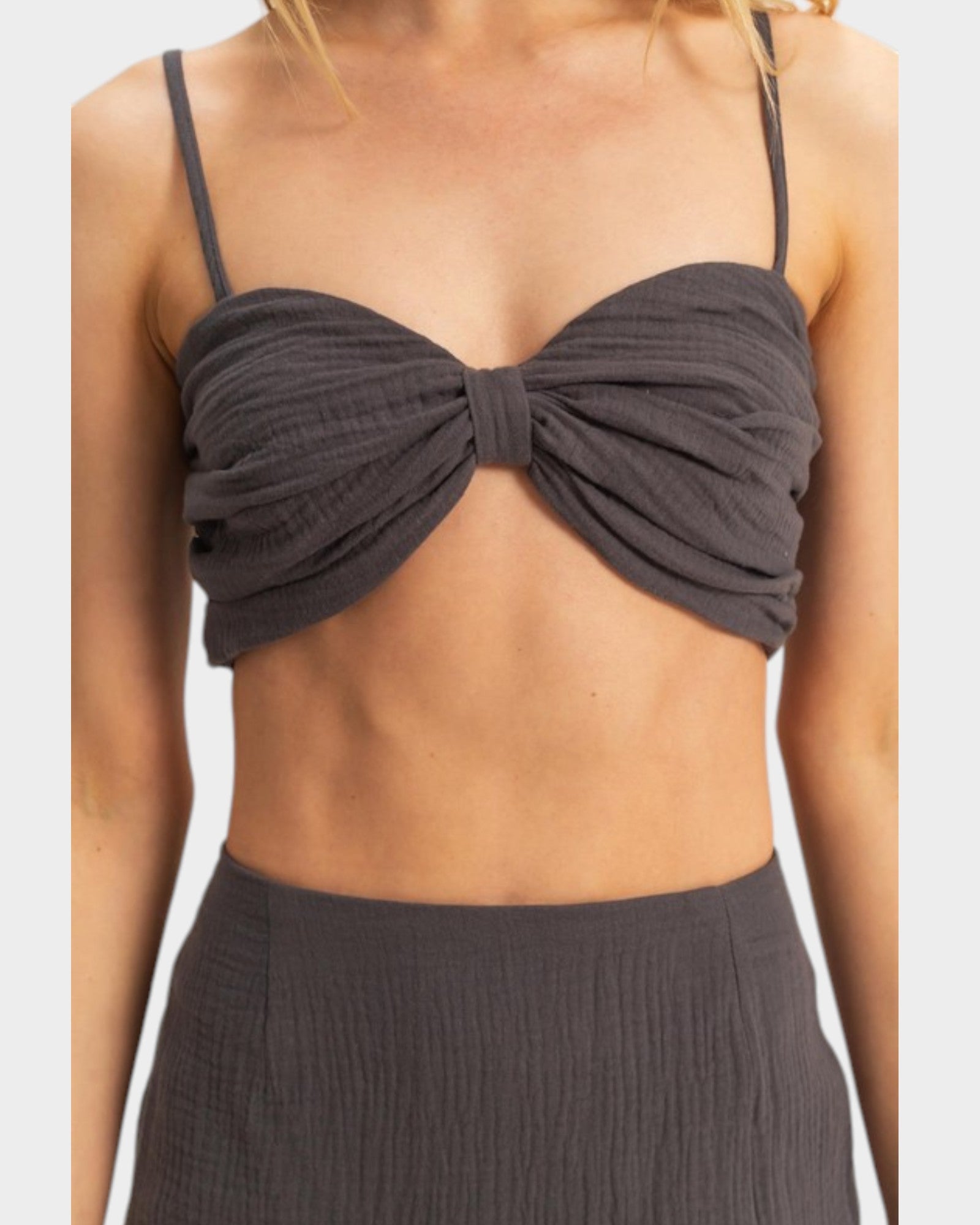 Dark gray bikini top with a knot detail on a neutral background