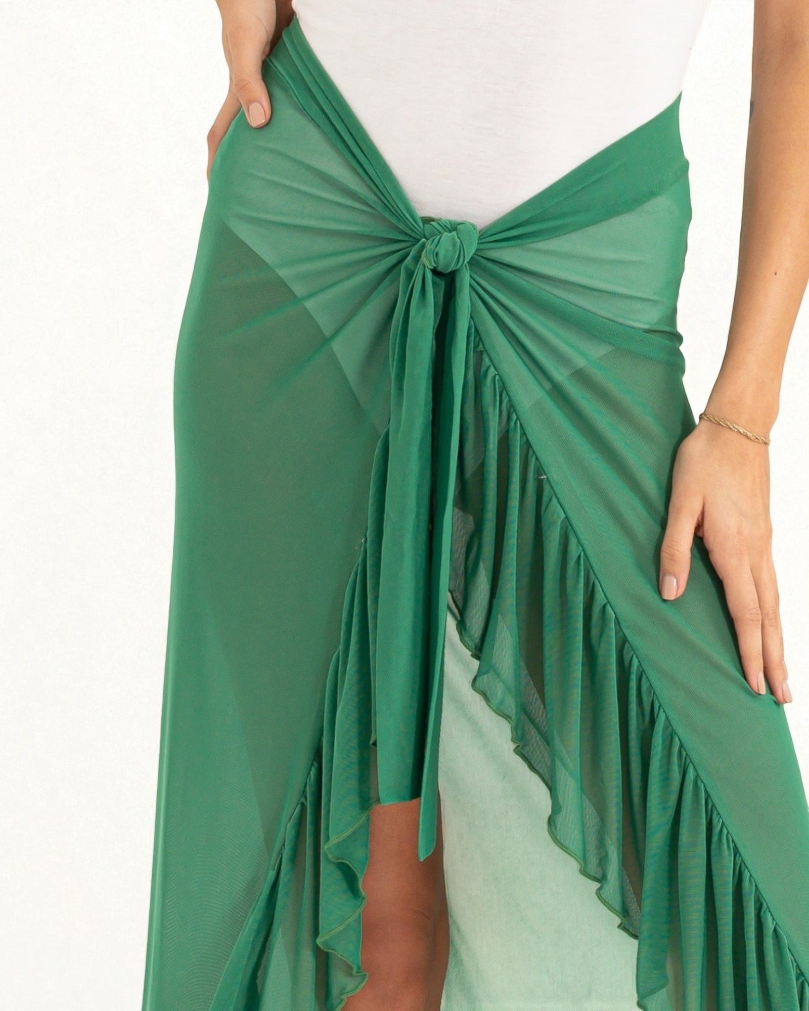 Green fringed wrap skirt worn over a white top on a white background