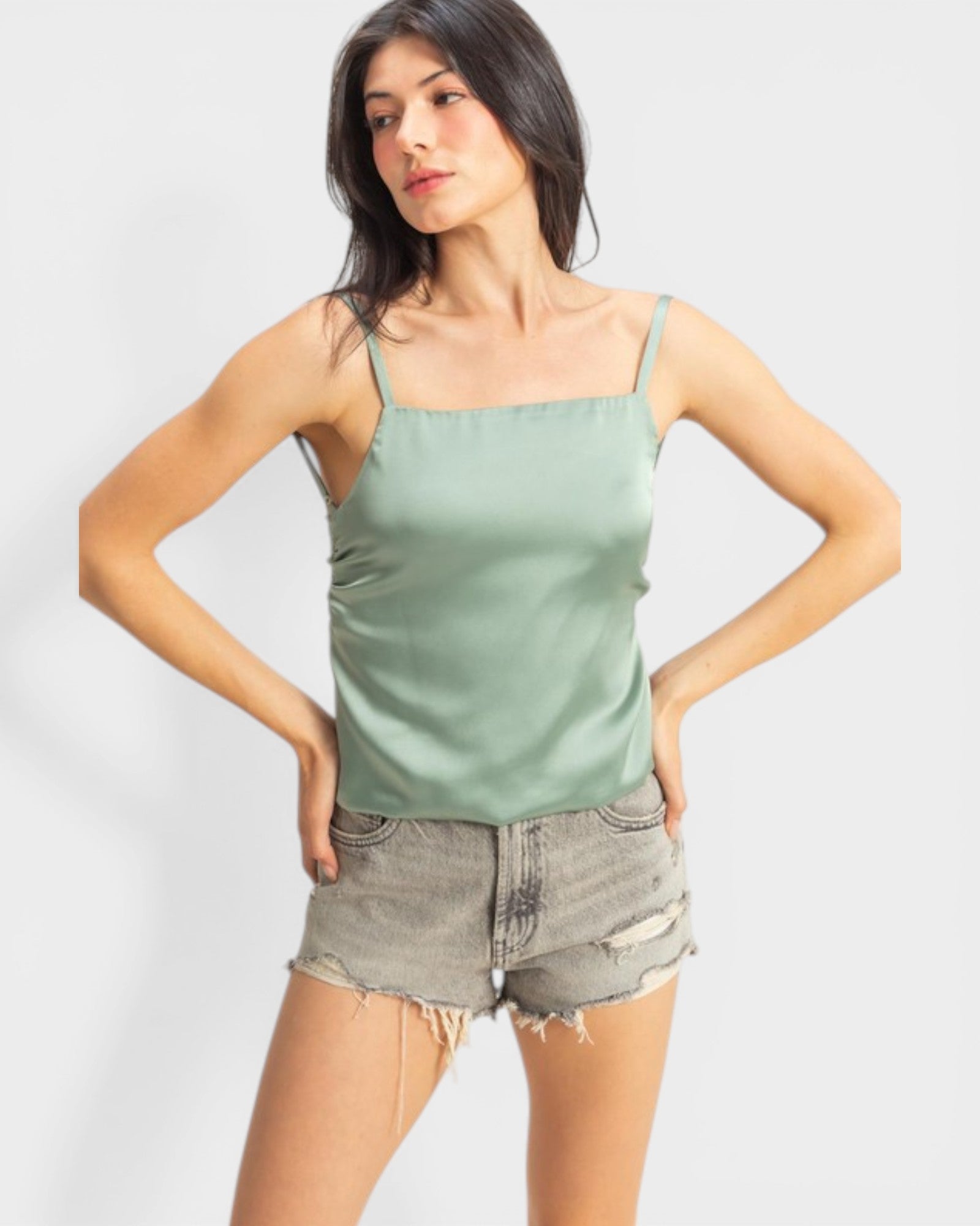 Woman wearing a green tank top and denim shorts on a white background