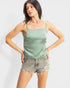 Woman wearing a green tank top and denim shorts on a white background