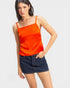 Woman wearing an orange tank top and denim skirt on a white background