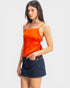 Woman wearing an orange top and denim skirt on a white background