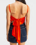Woman wearing an orange top with a bow and denim skirt on a white background