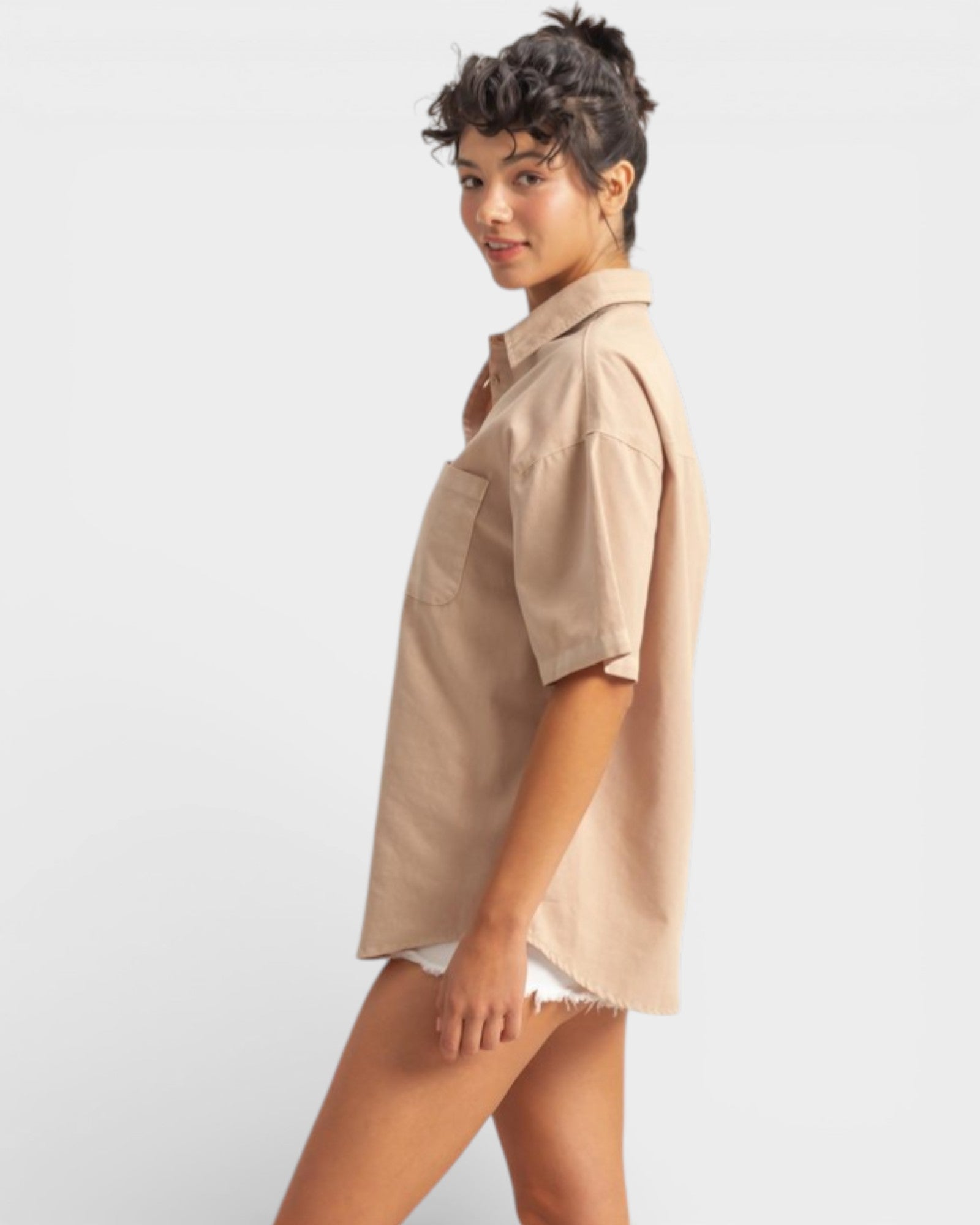 Woman wearing a beige shirt and white shorts on a plain background