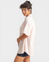 Woman wearing a light pink shirt and dark shorts on a white background