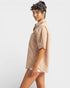 Woman wearing a beige shirt and white shorts on a plain background