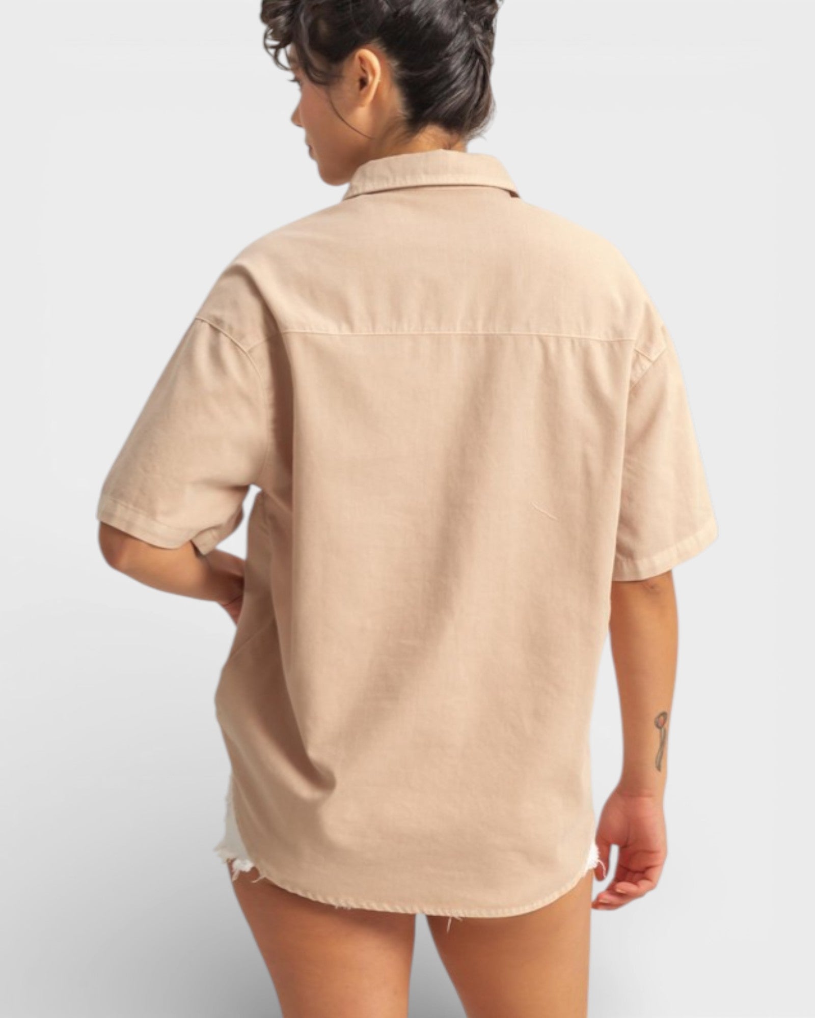 Person wearing a beige short-sleeve shirt on a light gray background