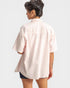 Person wearing a light pink oversized shirt on a white background