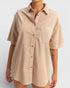 Beige short-sleeve shirt worn by a person on a light gray background