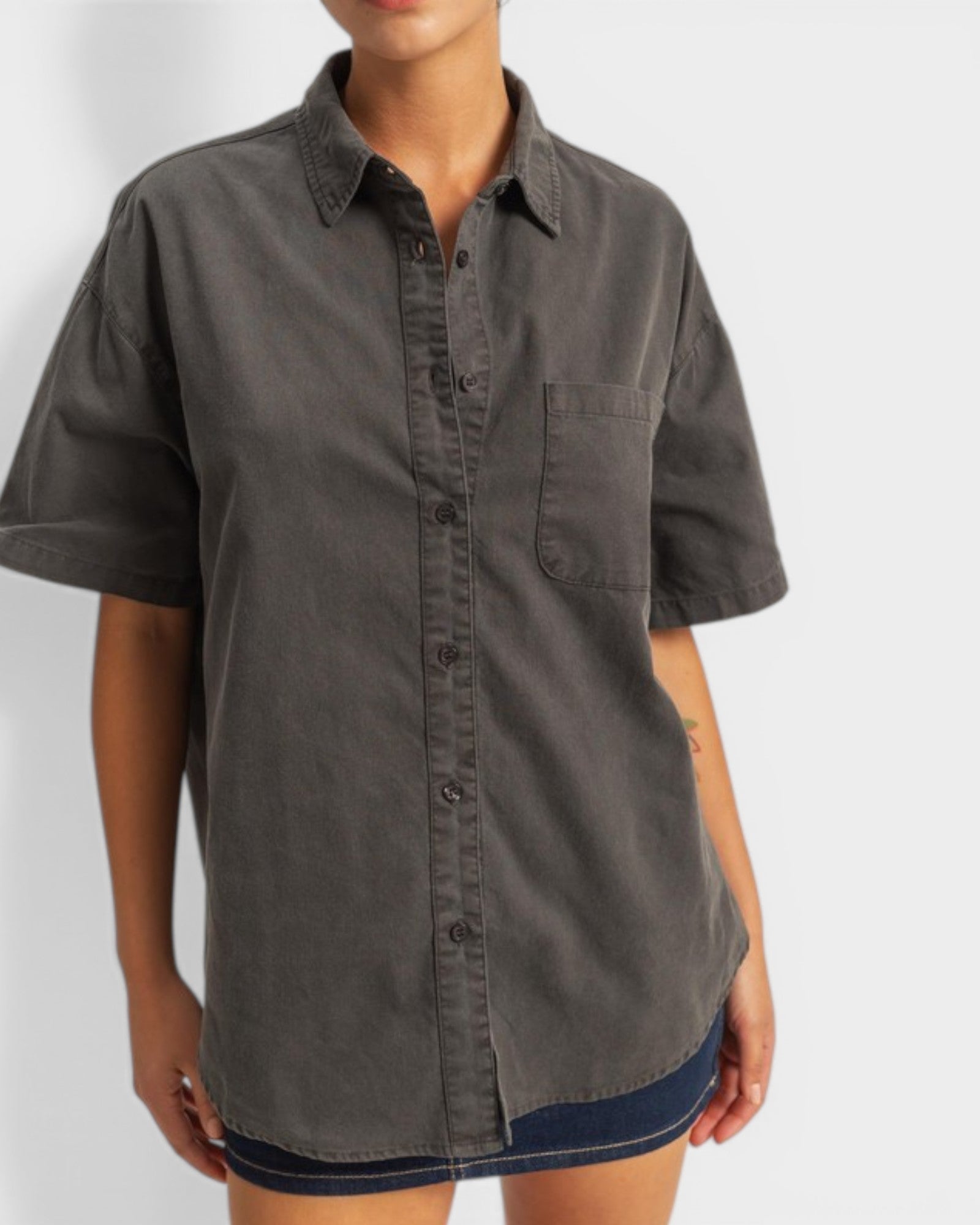 Person wearing a dark gray button-up shirt with short sleeves on a white background