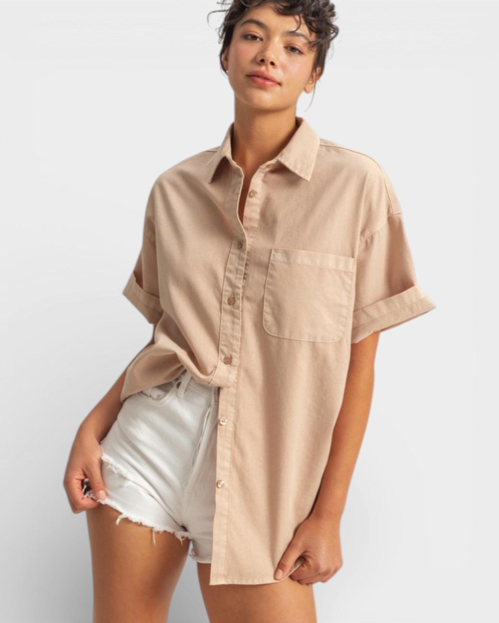 Woman wearing a beige button-up shirt and white shorts on a plain background