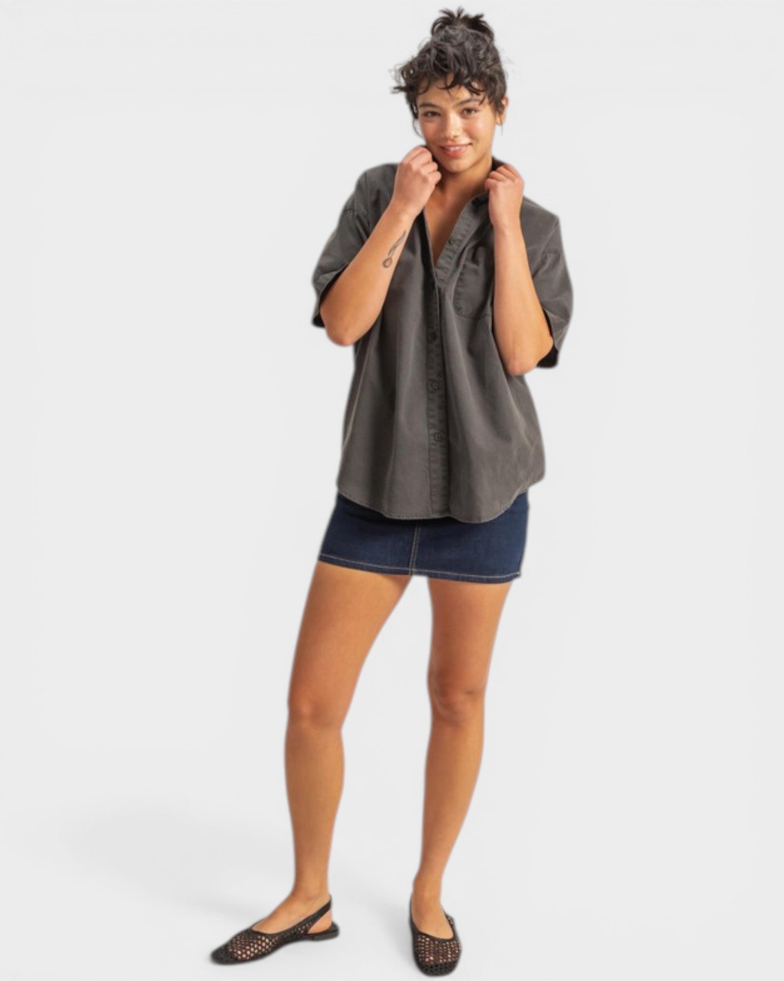 Woman wearing a gray shirt and denim skirt on a white background