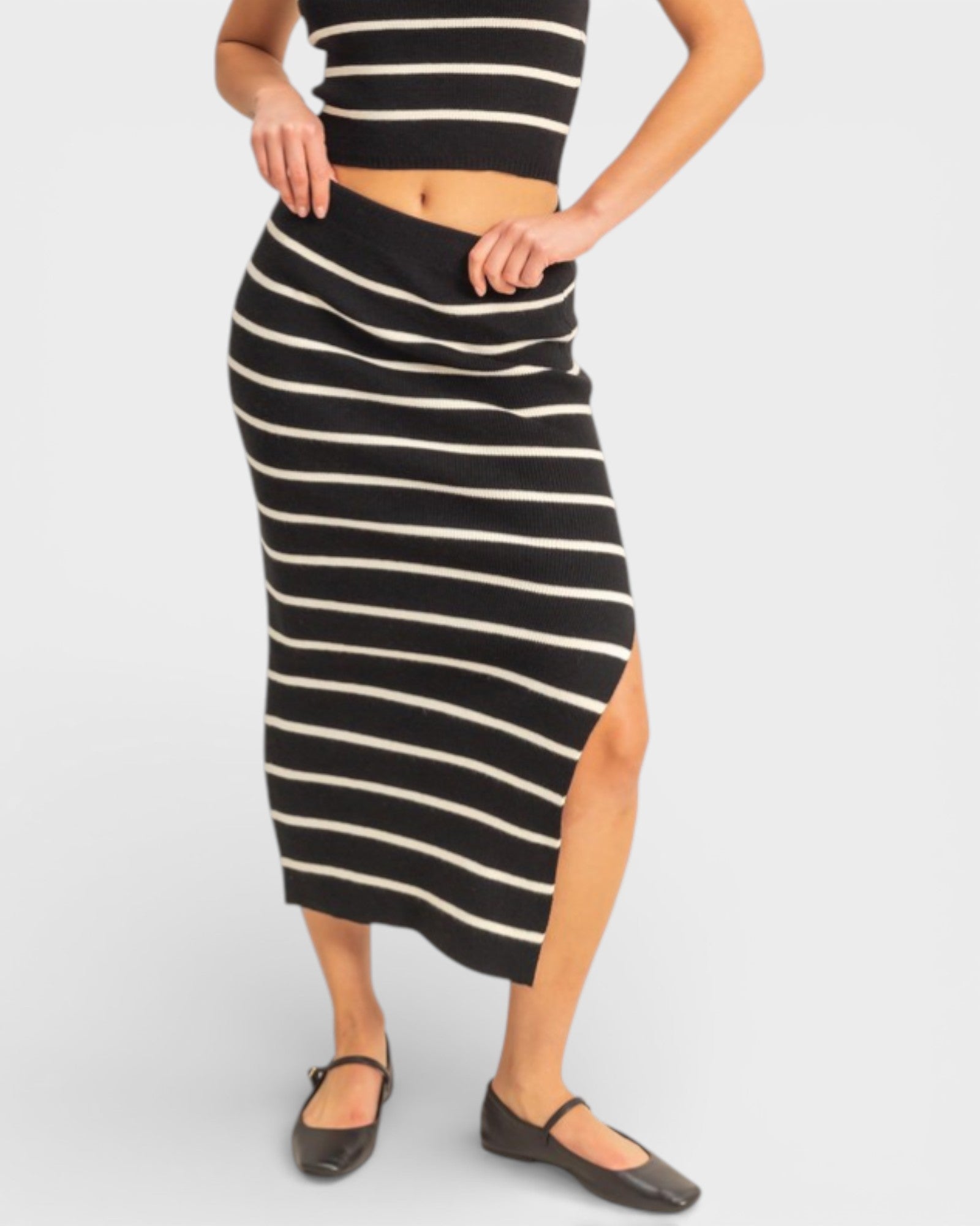 Person wearing a black and white striped skirt on a plain background