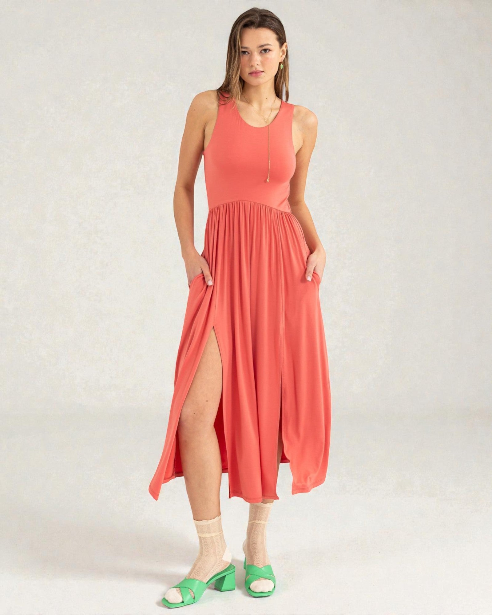 Woman wearing a coral dress with a slit on a white background