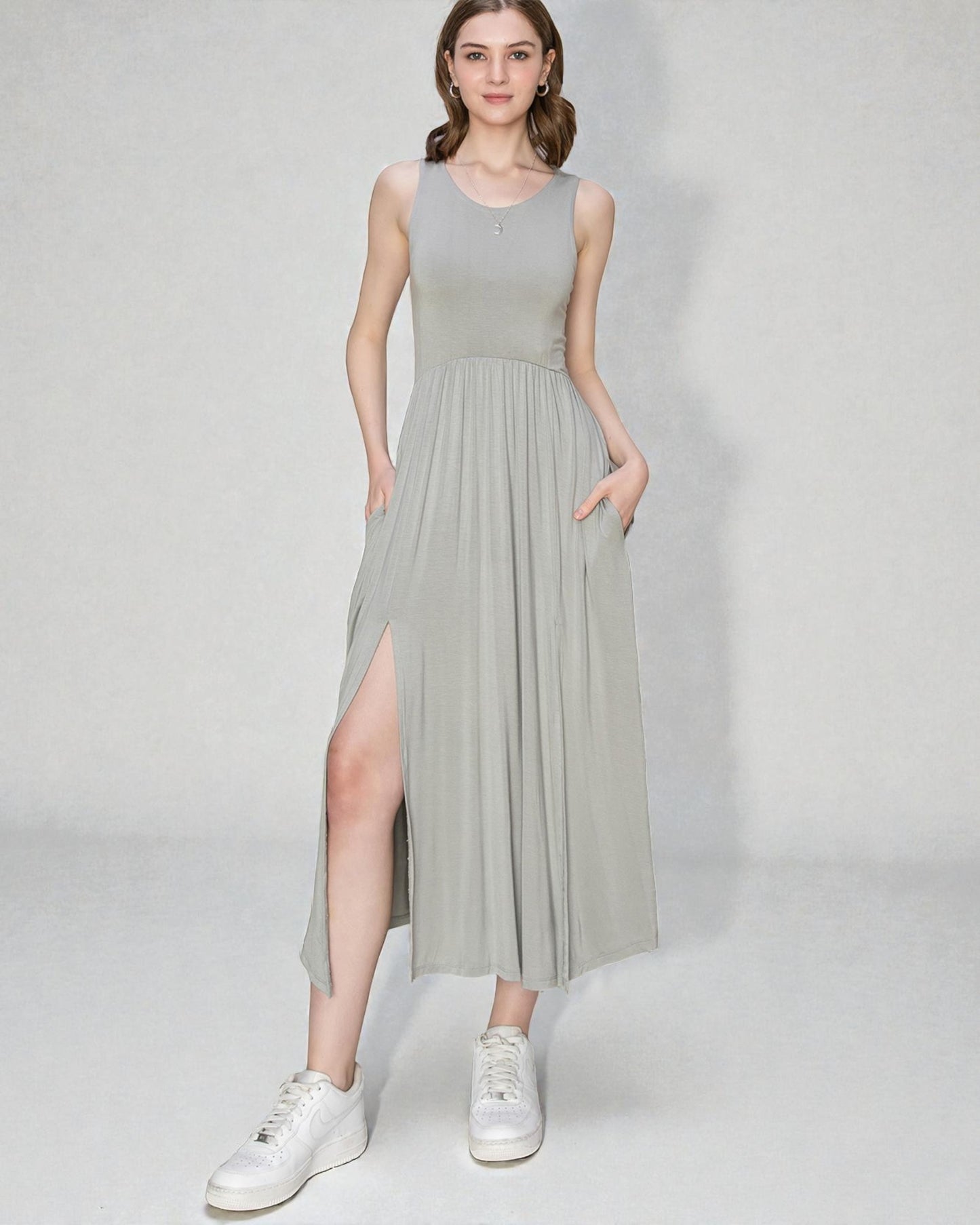 Woman wearing a light gray sleeveless dress with a slit on a white background
