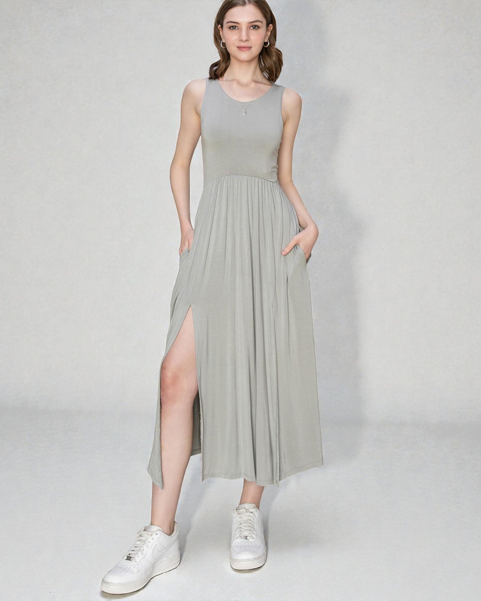 Woman wearing a light gray sleeveless dress with a slit on a white background