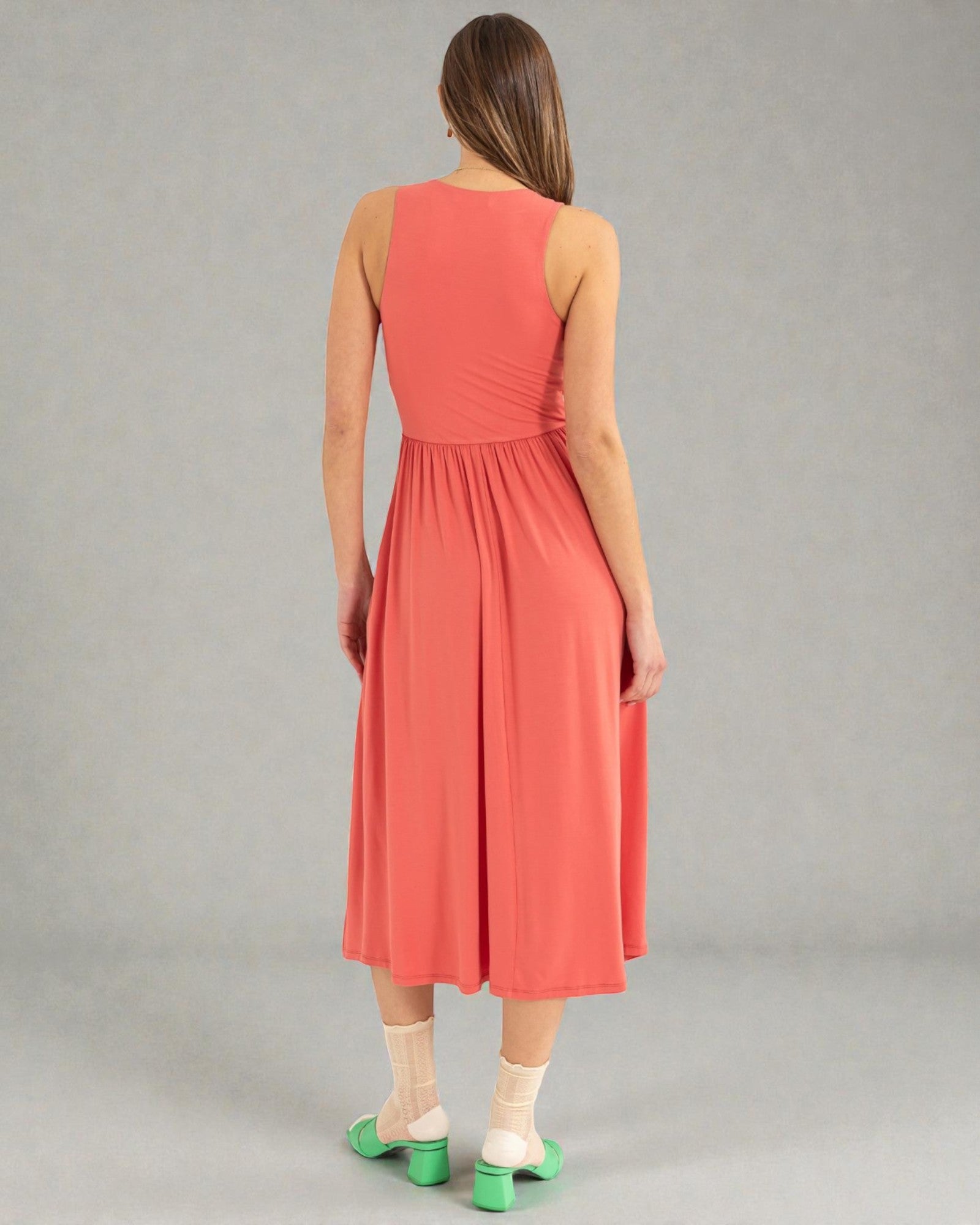 Woman wearing a coral dress on a gray background