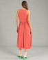 Woman wearing a coral dress on a gray background