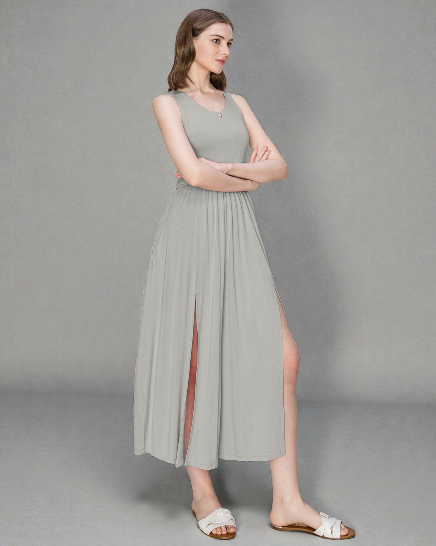 Woman wearing a light gray sleeveless dress with a slit on a gray background