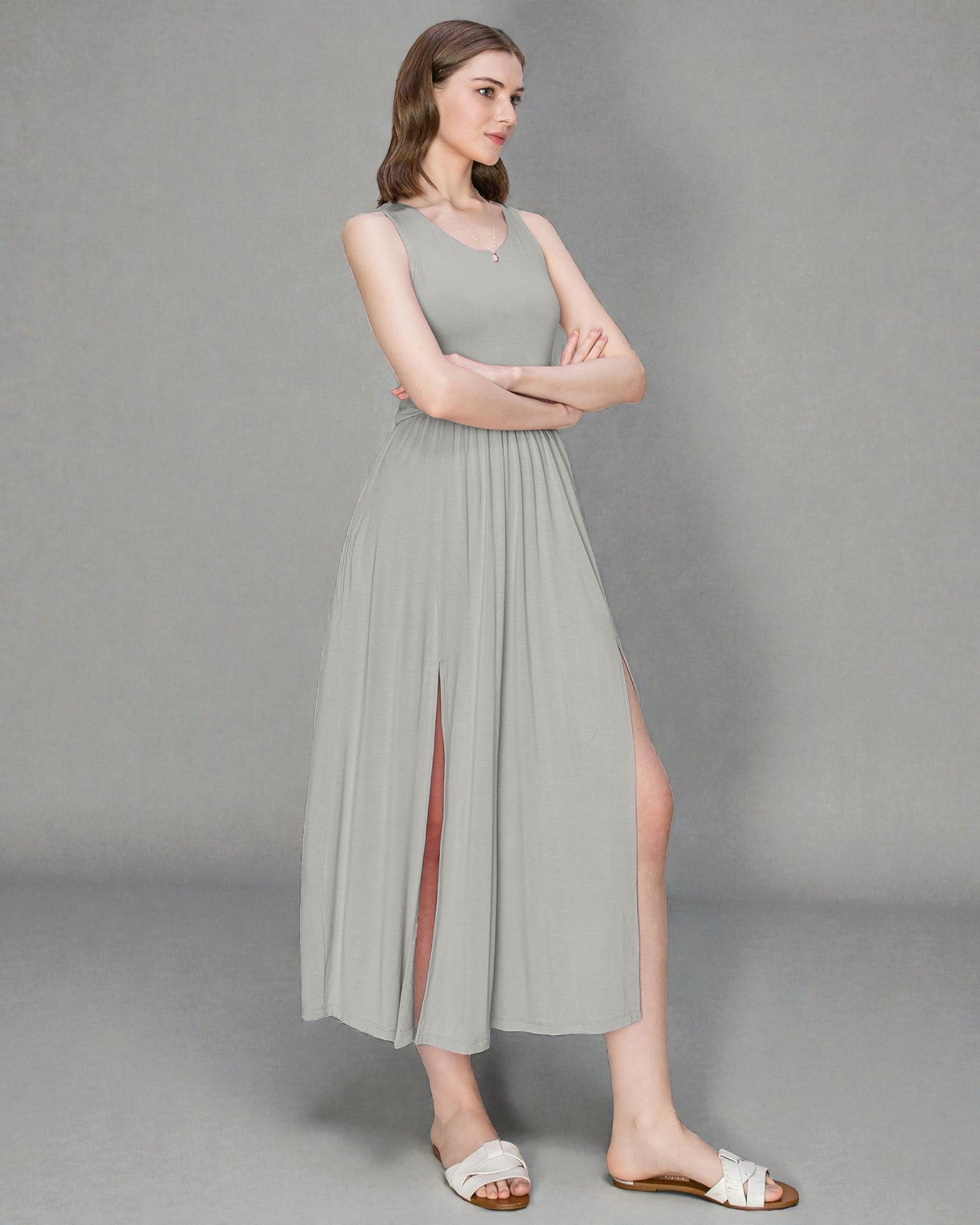 Woman wearing a light gray sleeveless dress with a slit on a gray background