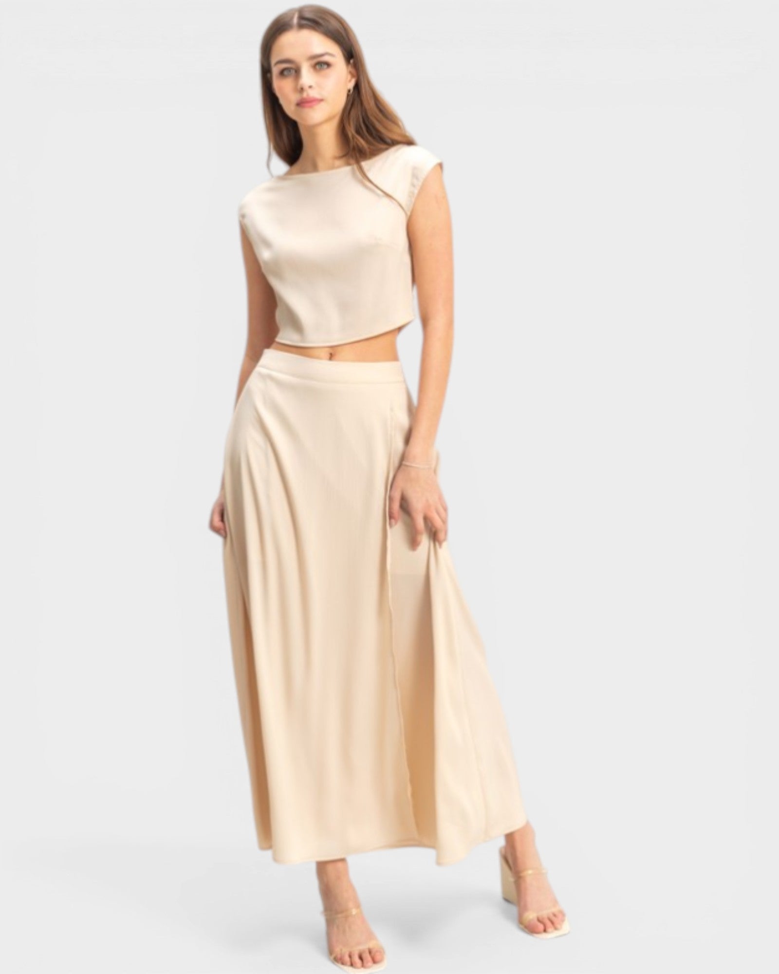 Woman wearing a beige sleeveless top and long skirt on a white background