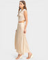 Woman wearing a beige sleeveless top and long skirt on a white background