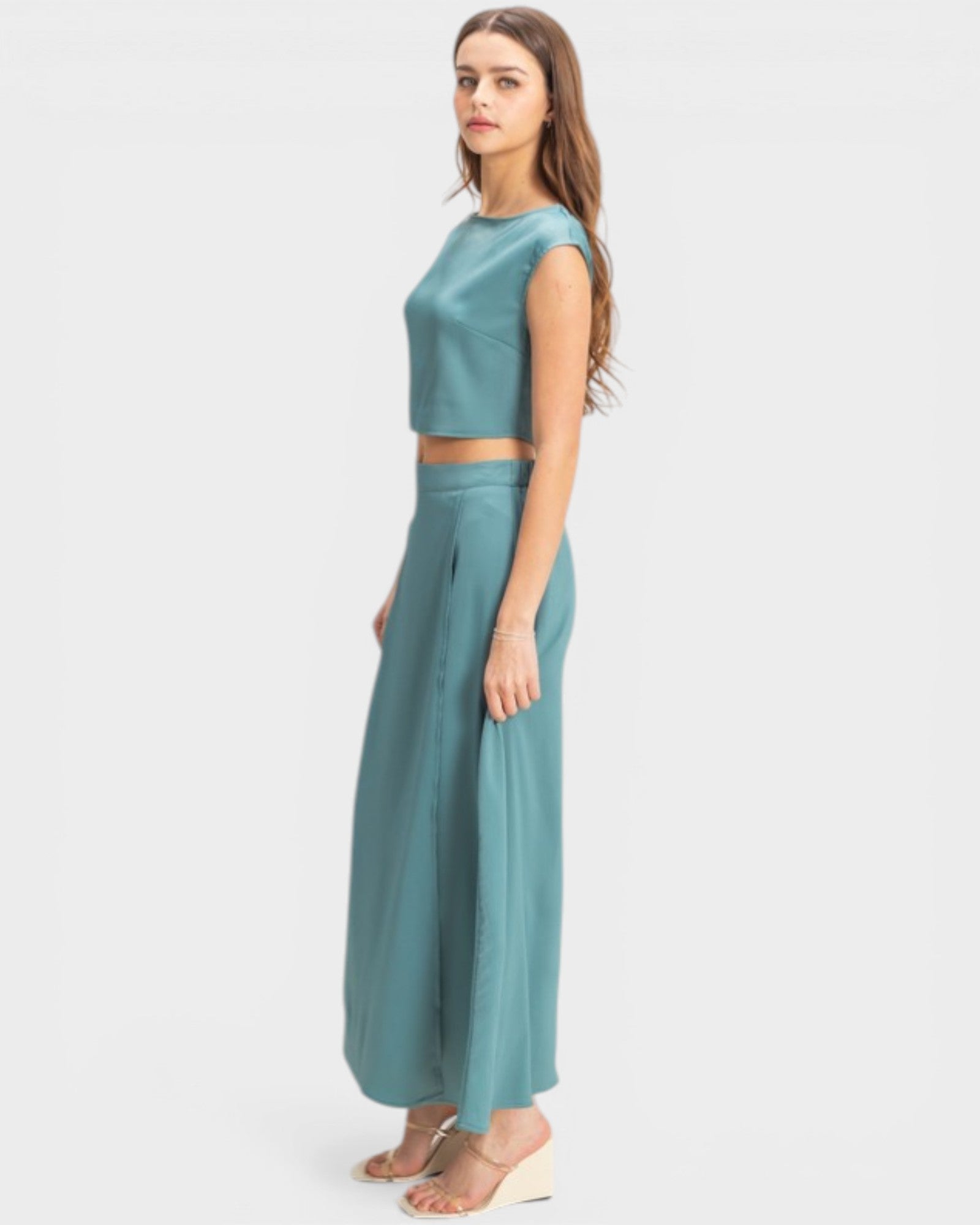 Woman wearing a teal two-piece outfit on a white background