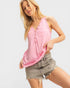 Woman wearing a pink sleeveless top and denim shorts on a white background