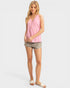 Woman wearing a pink sleeveless top and denim shorts on a white background