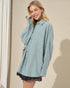 Woman wearing a light blue oversized shirt with a neutral background