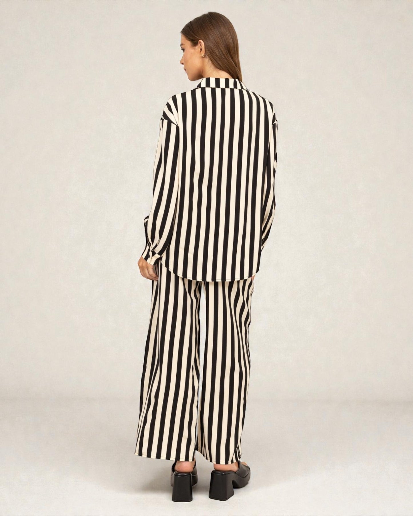 Person wearing a black and white striped outfit on a plain background