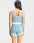 Woman wearing a blue and white striped sleeveless top and shorts on a light gray background