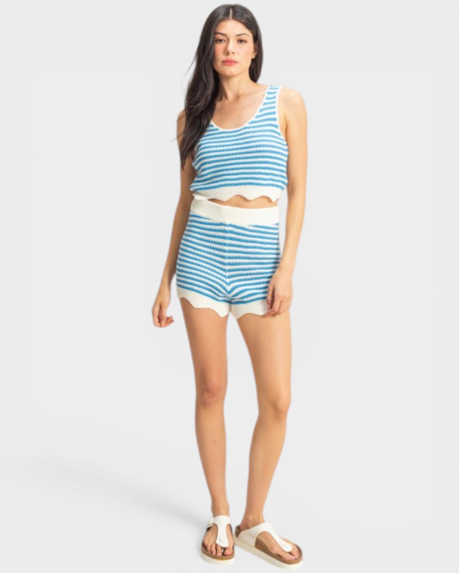 Woman wearing a blue and white striped tank top and shorts on a white background