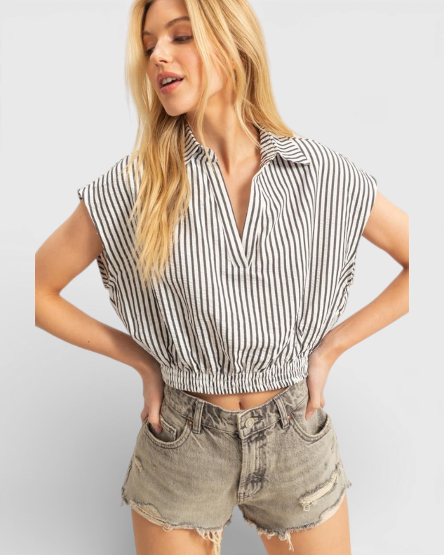 Woman wearing a striped shirt and shorts on a plain background