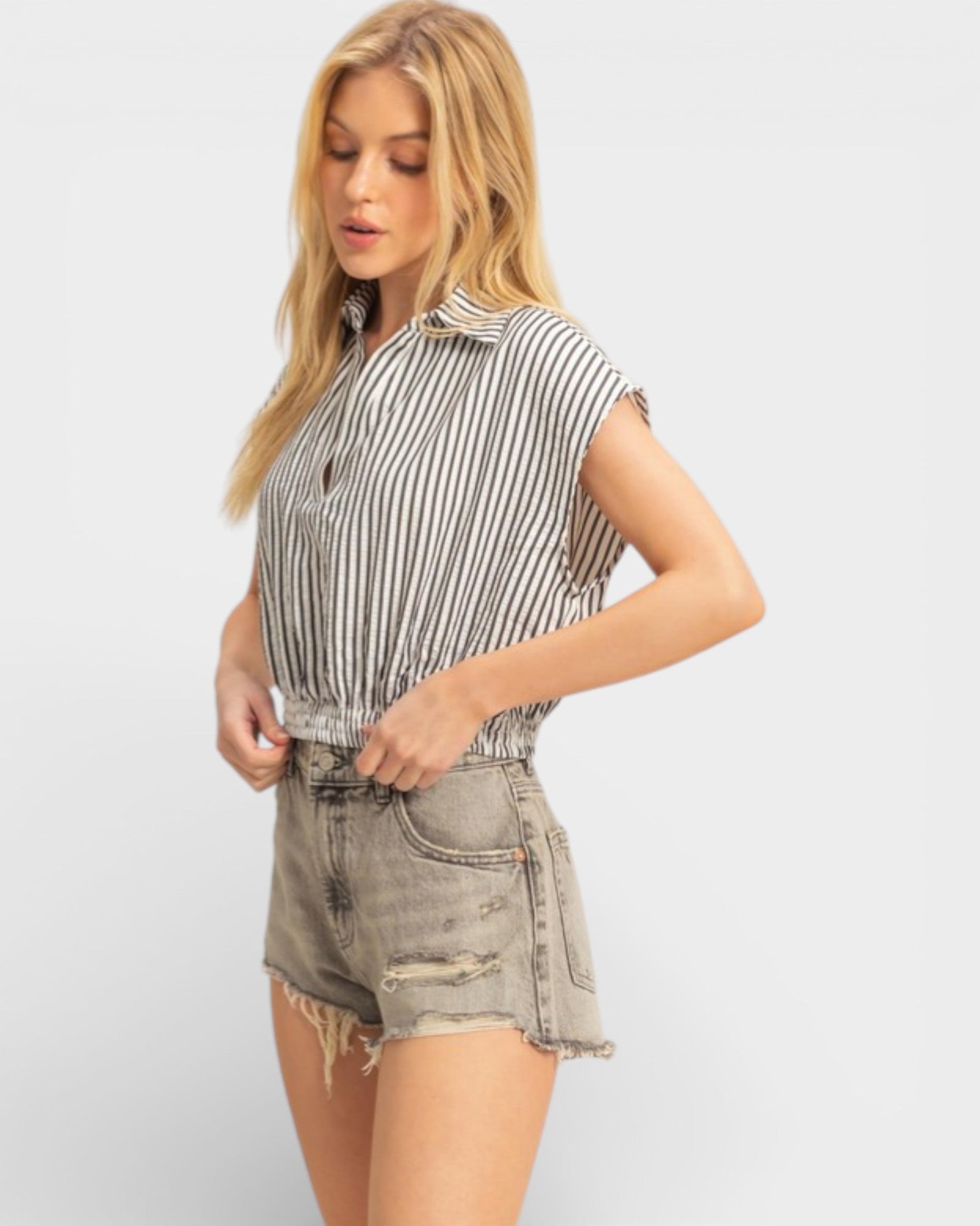 Woman wearing a striped shirt and denim shorts on a white background